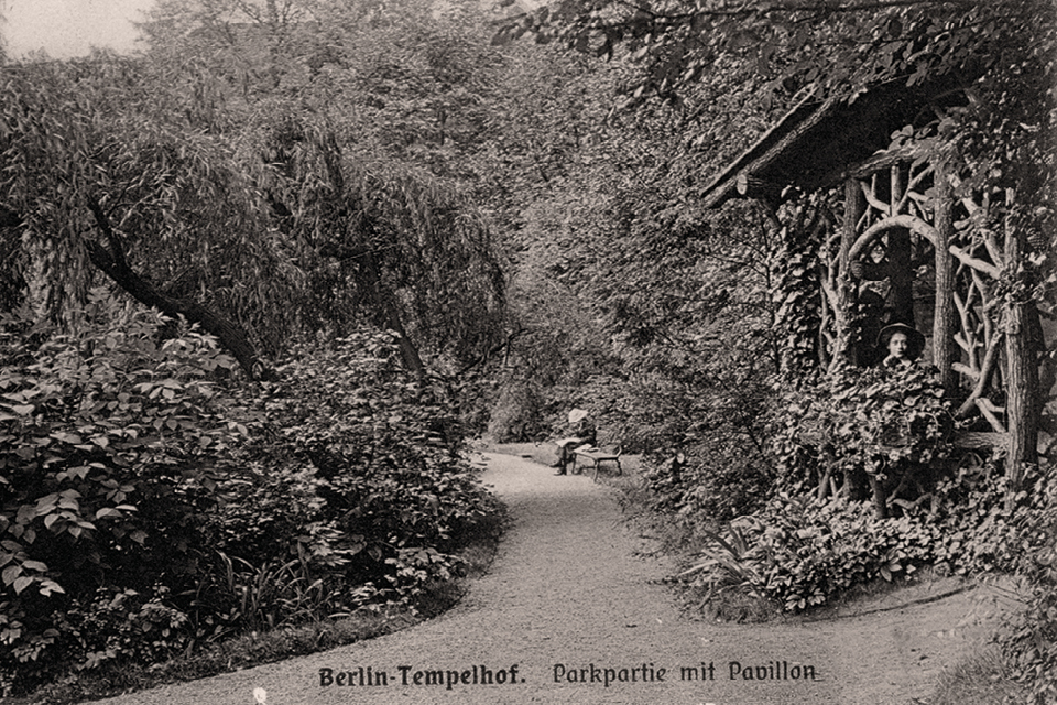 An der Mauer der Dorfkirche und am Rand des Wilhelmsteichs befand sich Anfang des 20. Jahrhunderts ein Holzpavillon. © Museen Tempelhof-Schöneberg/Archiv Kunstverlag J. Goldiner