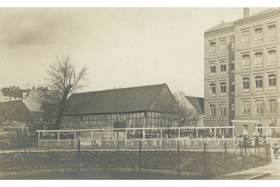 Die Postkarte zeigt den Blick auf den Reinhardtplatz mit dem Grundpfuhl und einer ehemaligen angrenzenden Luise-Henriette-Schule um 1905. © Museen Tempelhof-Schöneberg/Archiv